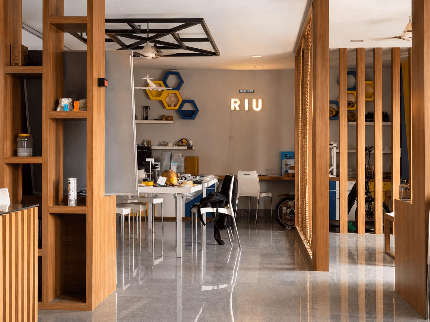 A study room of light wood partitions and hexagon shelving, tables laid out inside