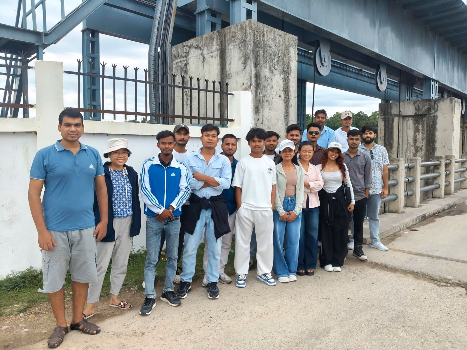 A student group standing under a road bridge on a site visit, its girder and pier overhead