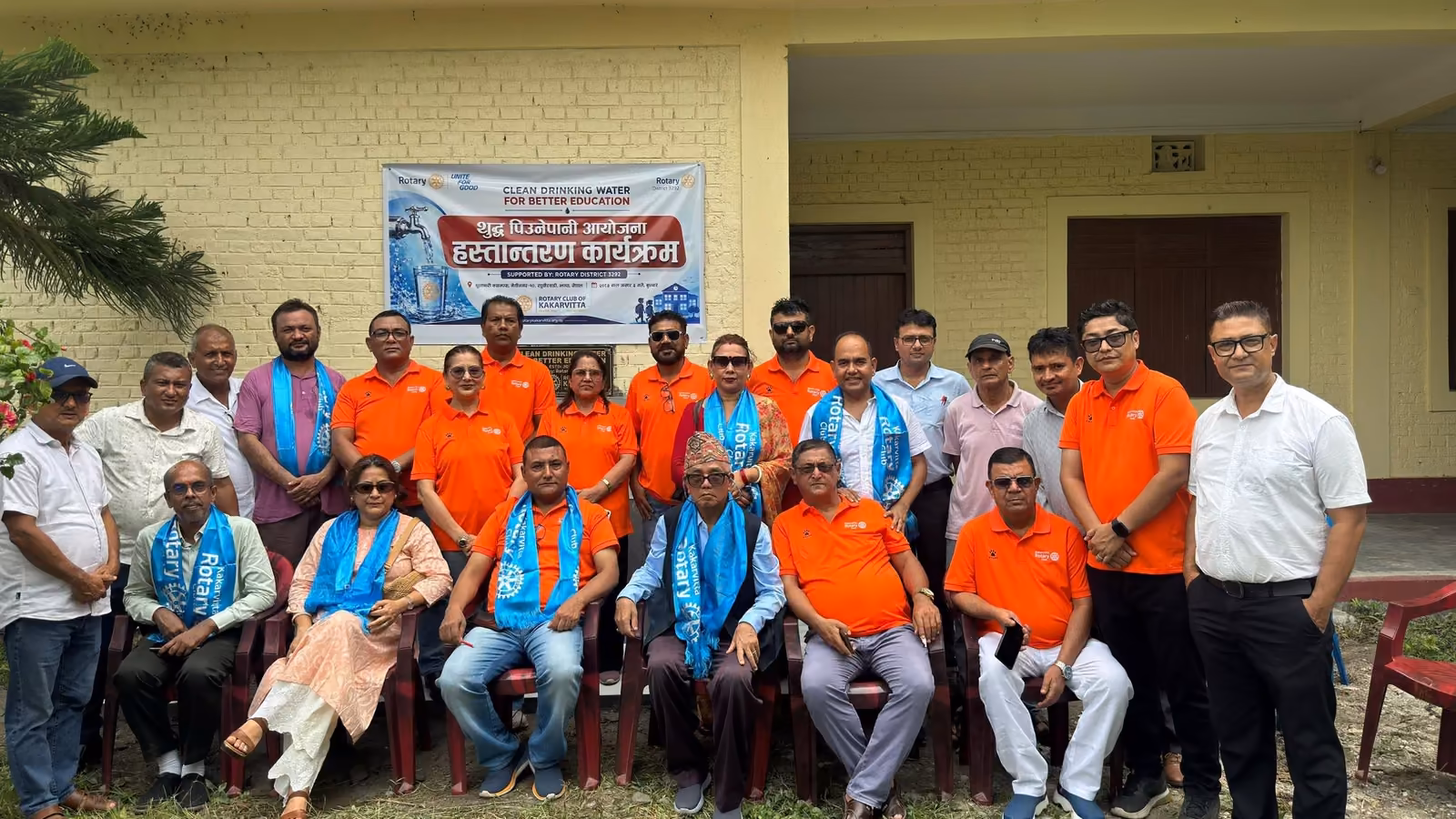Participants of a handover programme seated and standing in front of the campus block