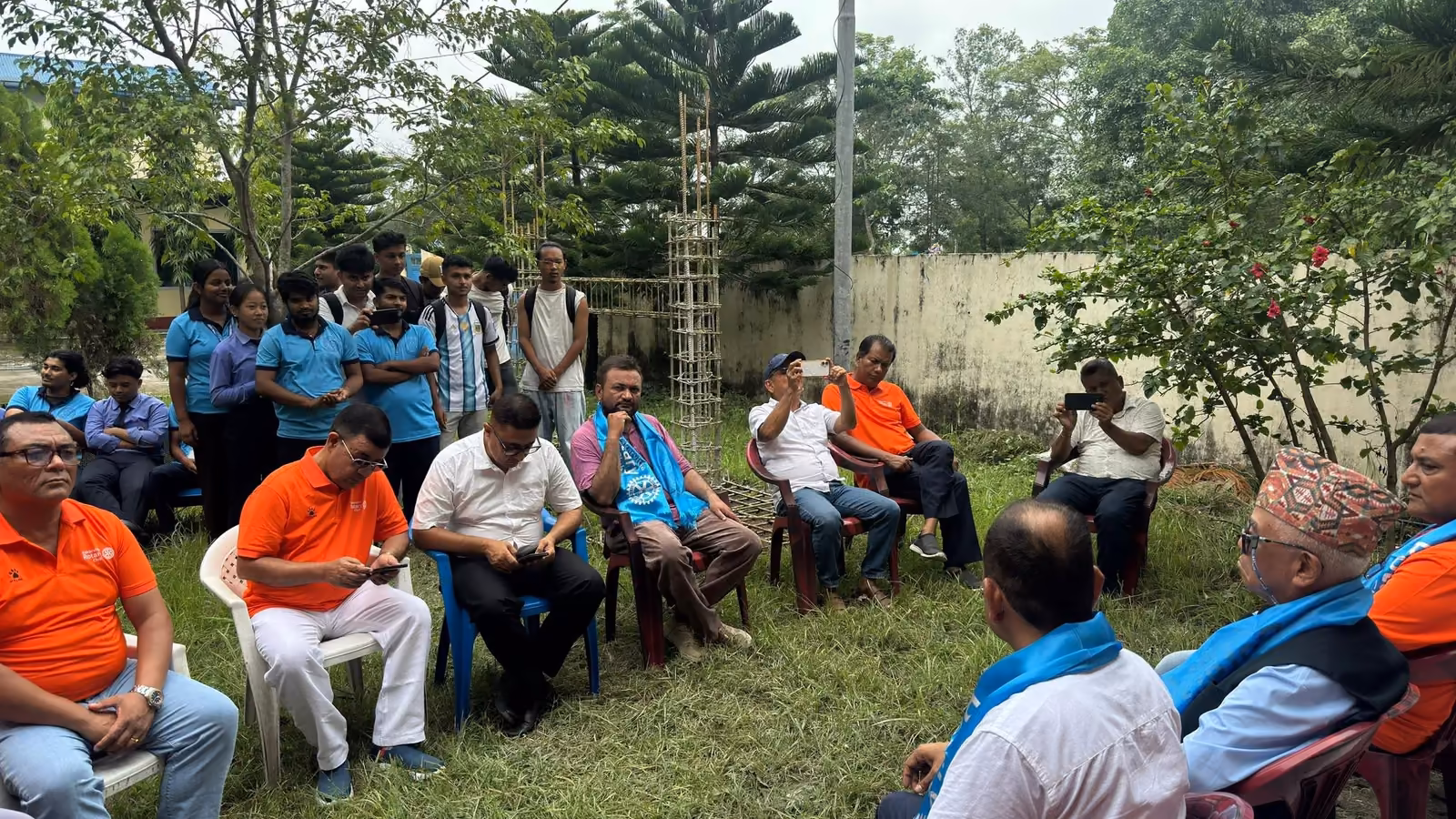 Guests seated on chairs under the trees on the campus grounds
