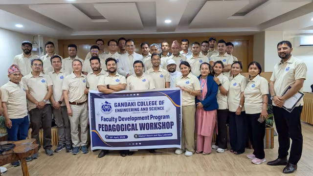 Participants of a faculty development workshop holding its banner in a hall