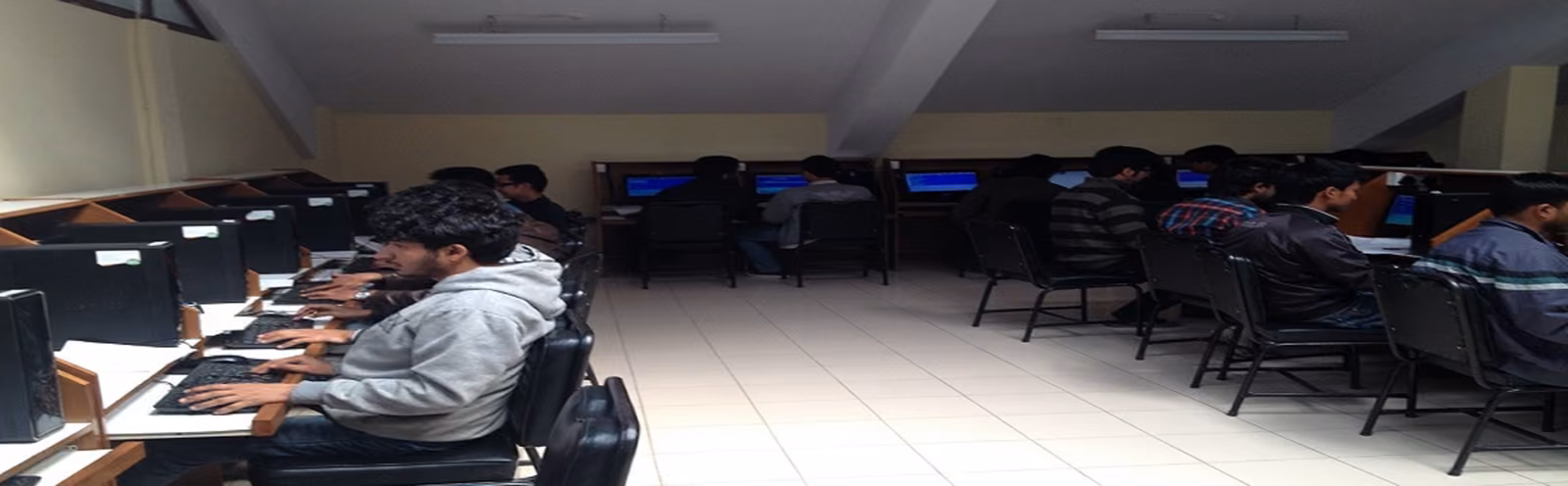 Students at computers along the desks of a long laboratory, chairs pushed in beyond