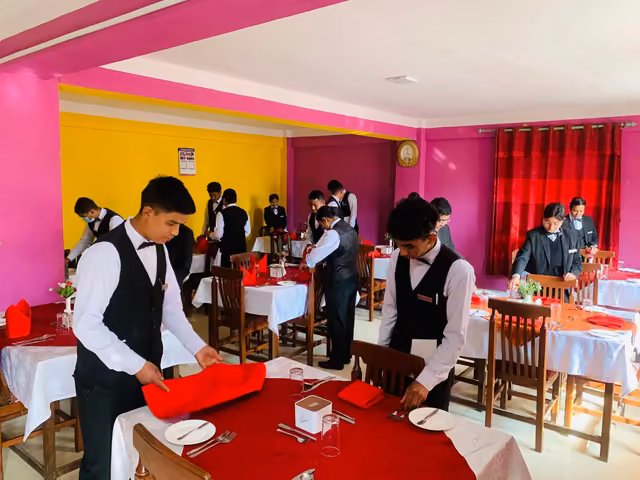 Students in waistcoats laying the tables in the training restaurant