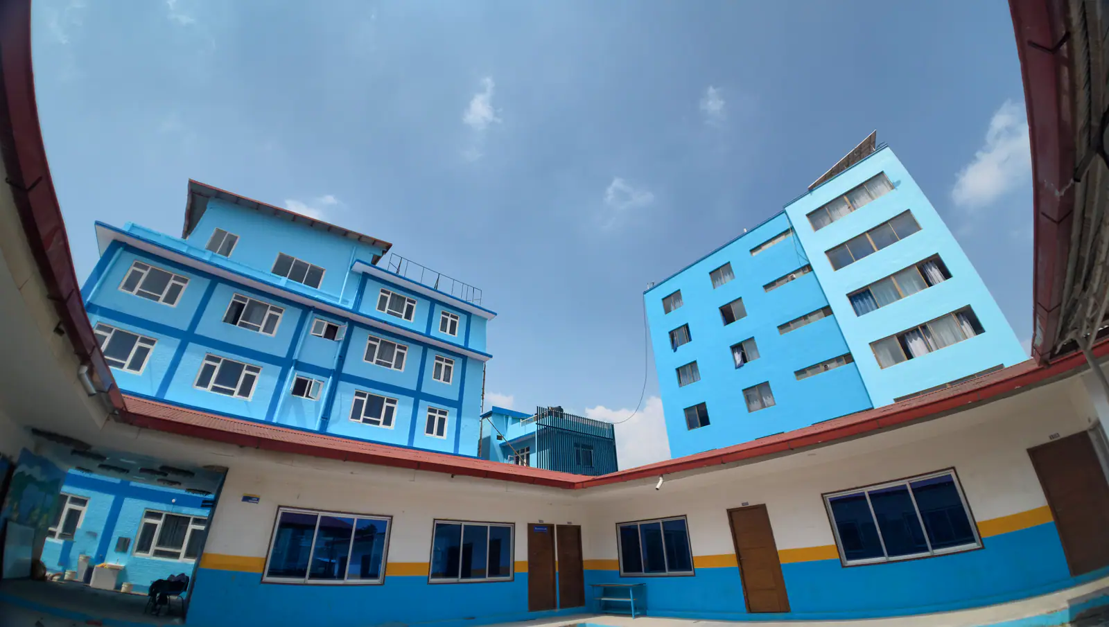 The college's blue and white block from below, its balconies stacked to the roofline