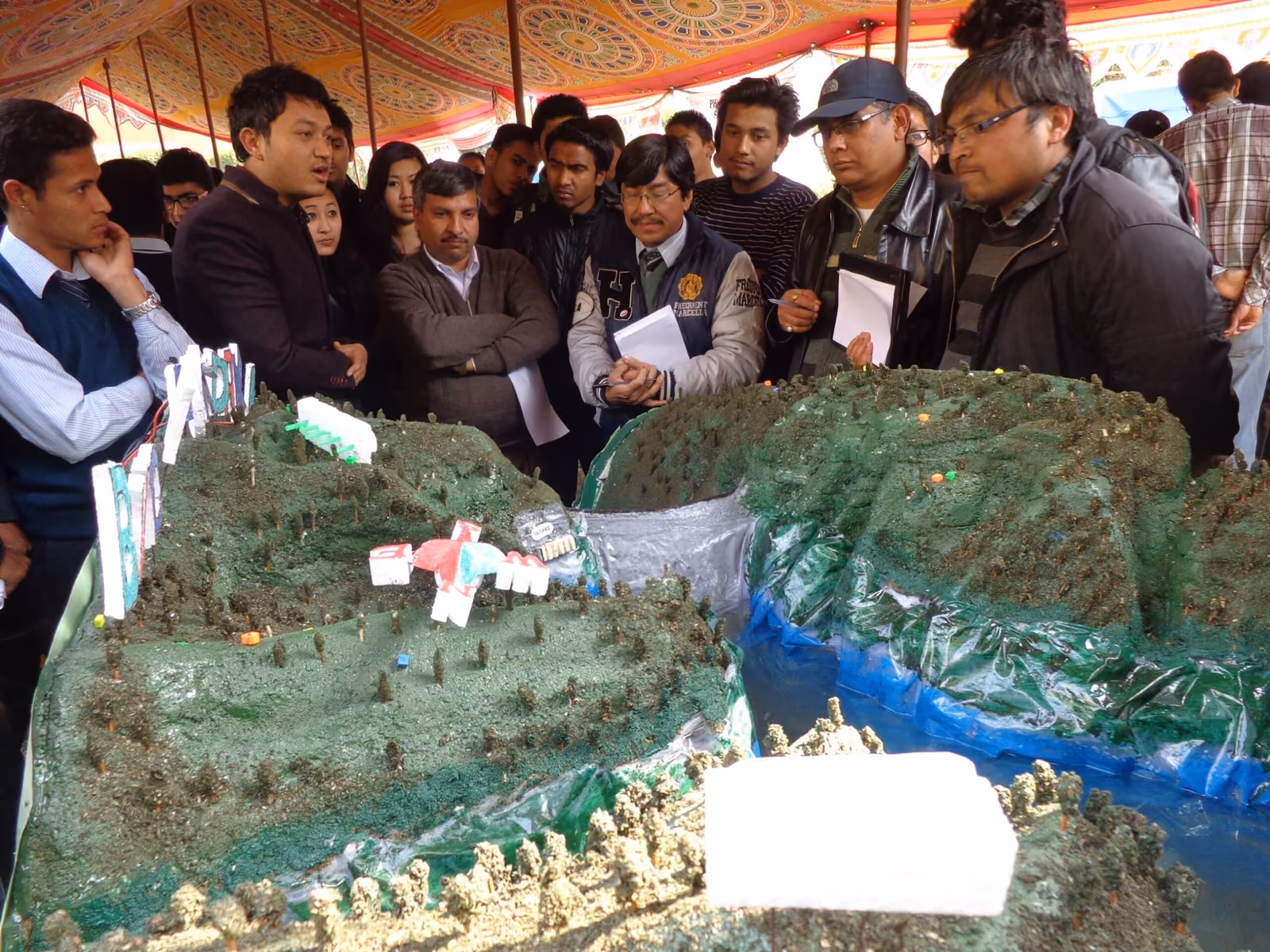 Visitors round a large terrain model of a valley, a bridge and buildings set into it