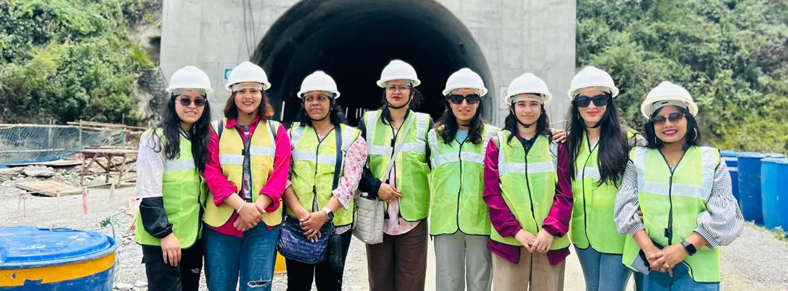 Eight students in hi-vis vests and hard hats at a tunnel portal on a construction site