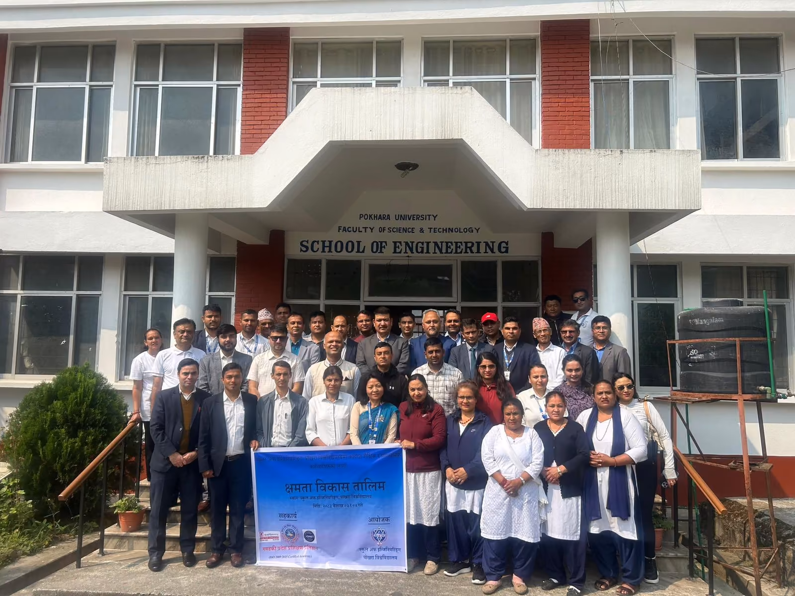 Staff and students in a group photograph under the Faculty of Science and Technology signboard