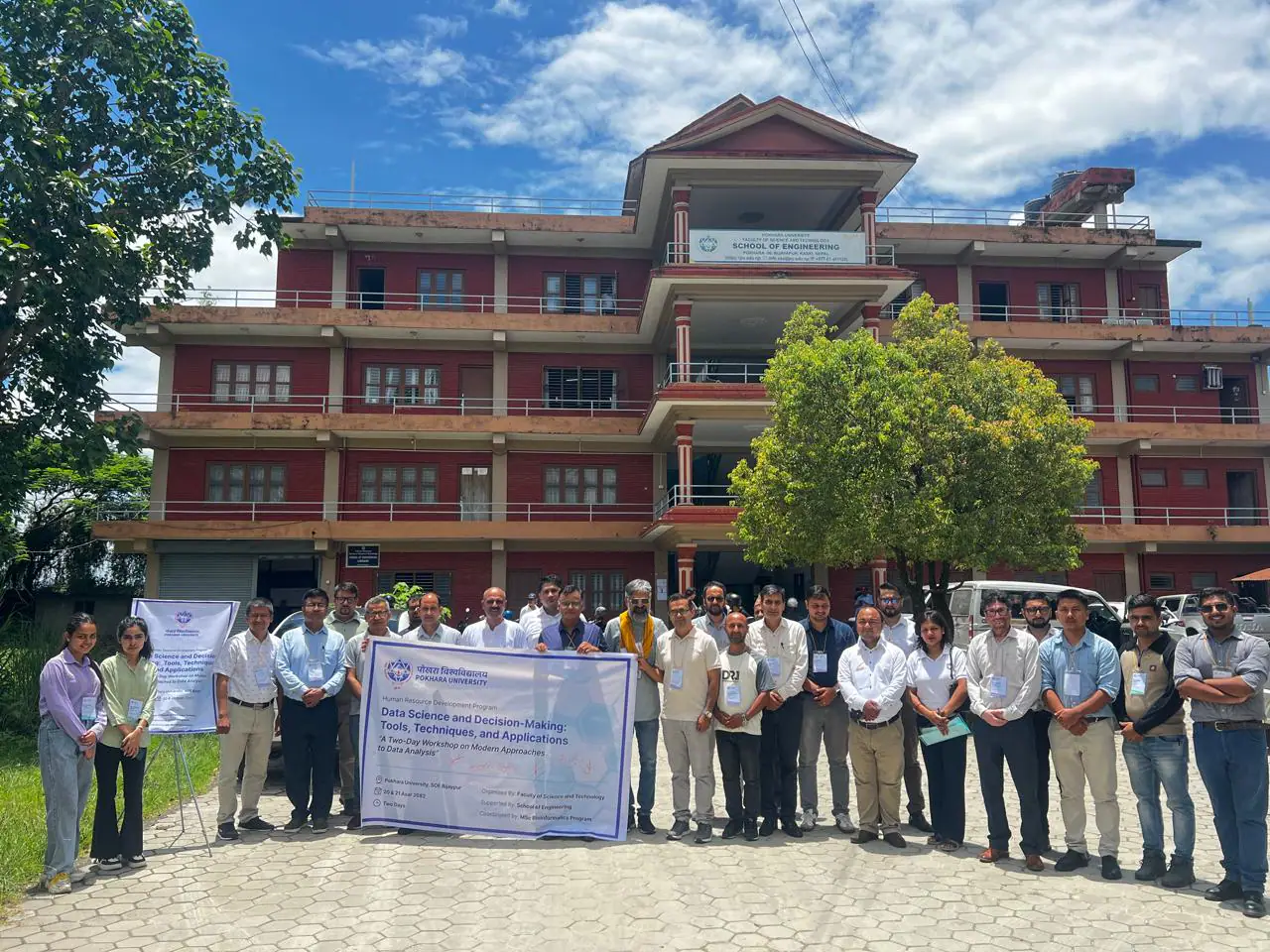 The school's red-brick block behind its signboard, a group photographed on the lawn in front of it
