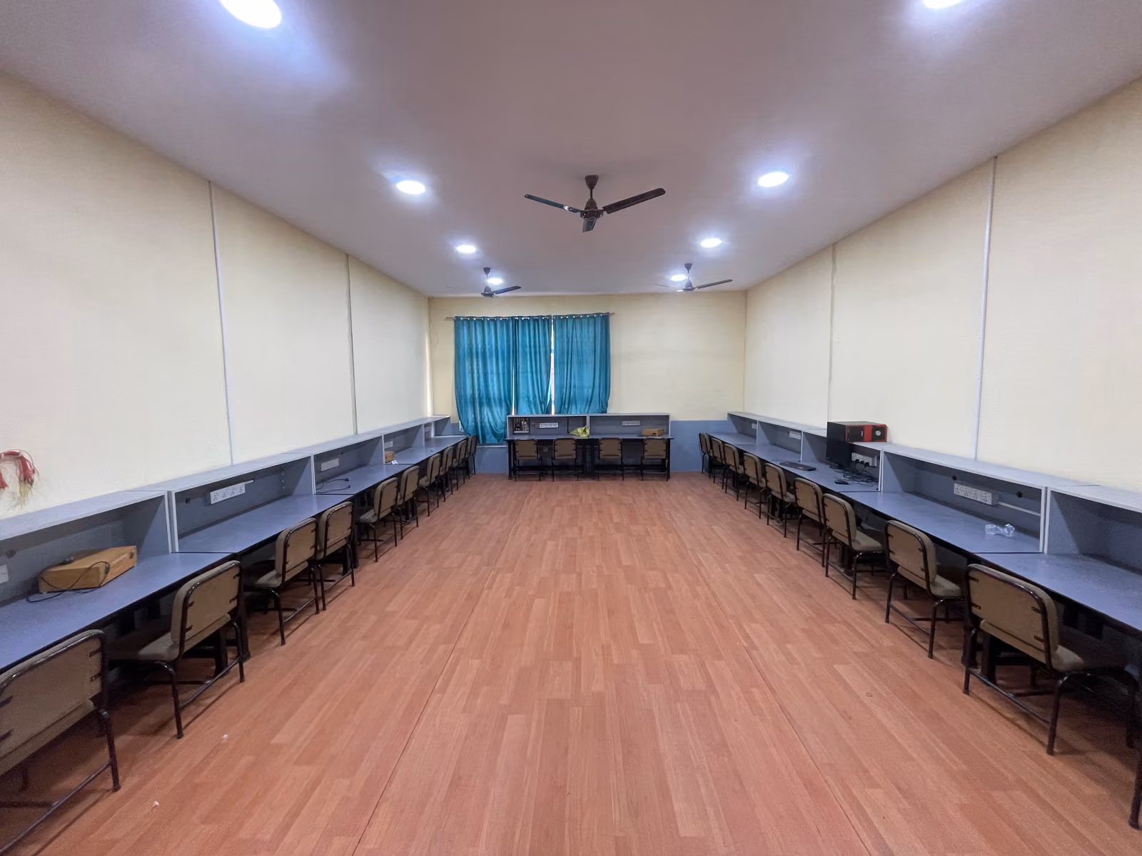 An empty laboratory, benches down both walls under a wooden floor and strip lights