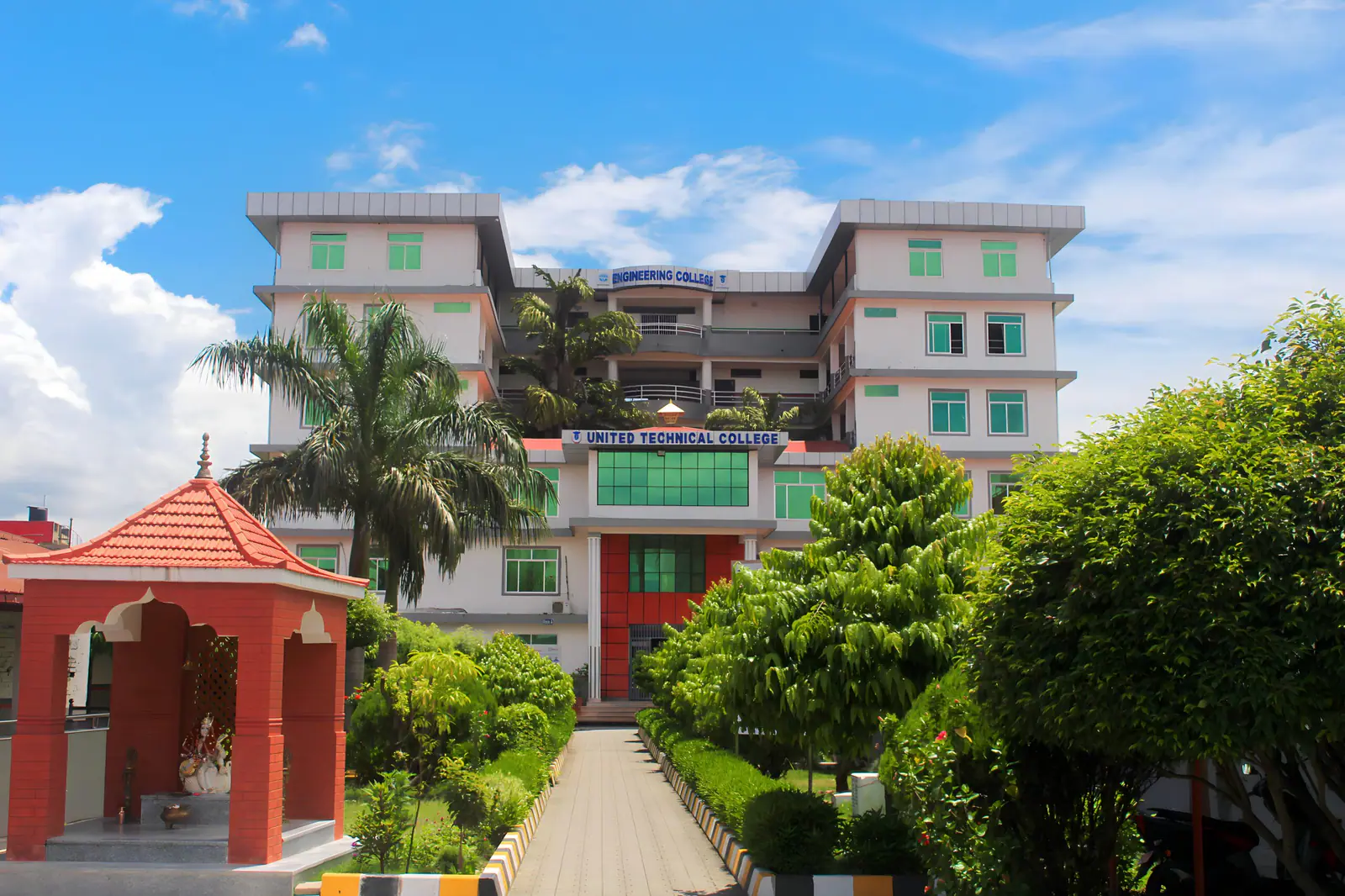 The college's white block behind a red pagoda gateway, clipped hedges along the path