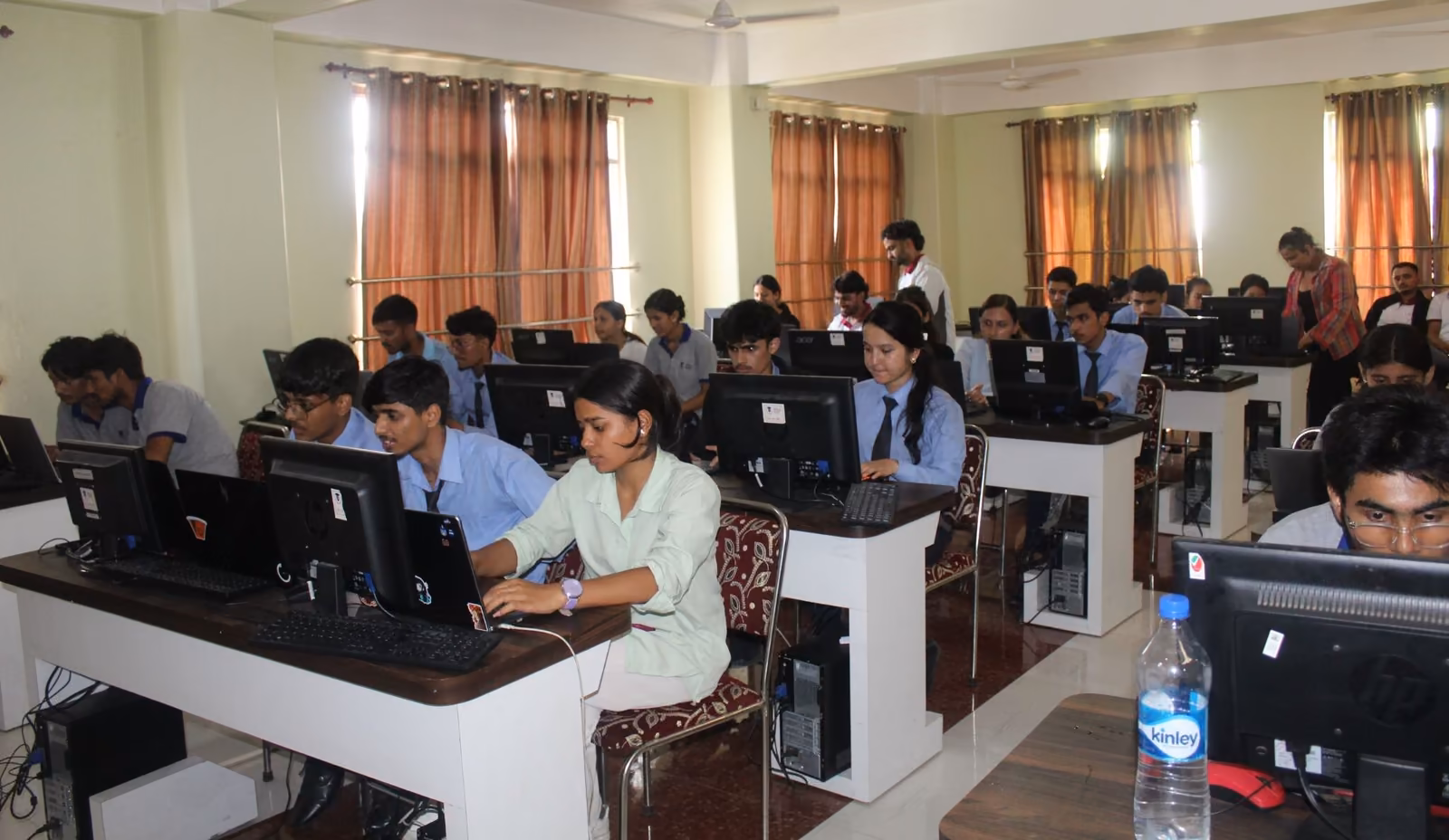 Students at rows of desktop computers in a curtained laboratory, a workshop in progress